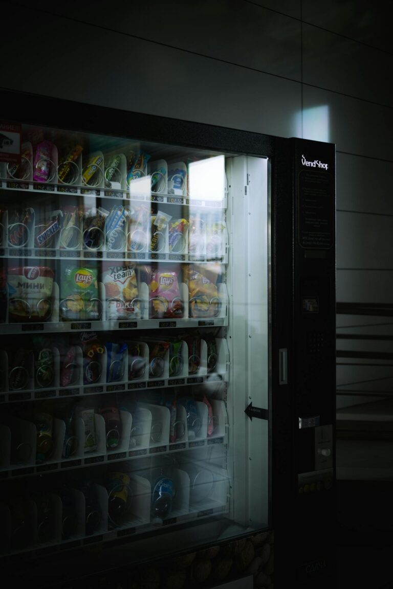 A vending machine indoors with snacks and drinks in a dimly lit environment, creating a moody atmosphere.